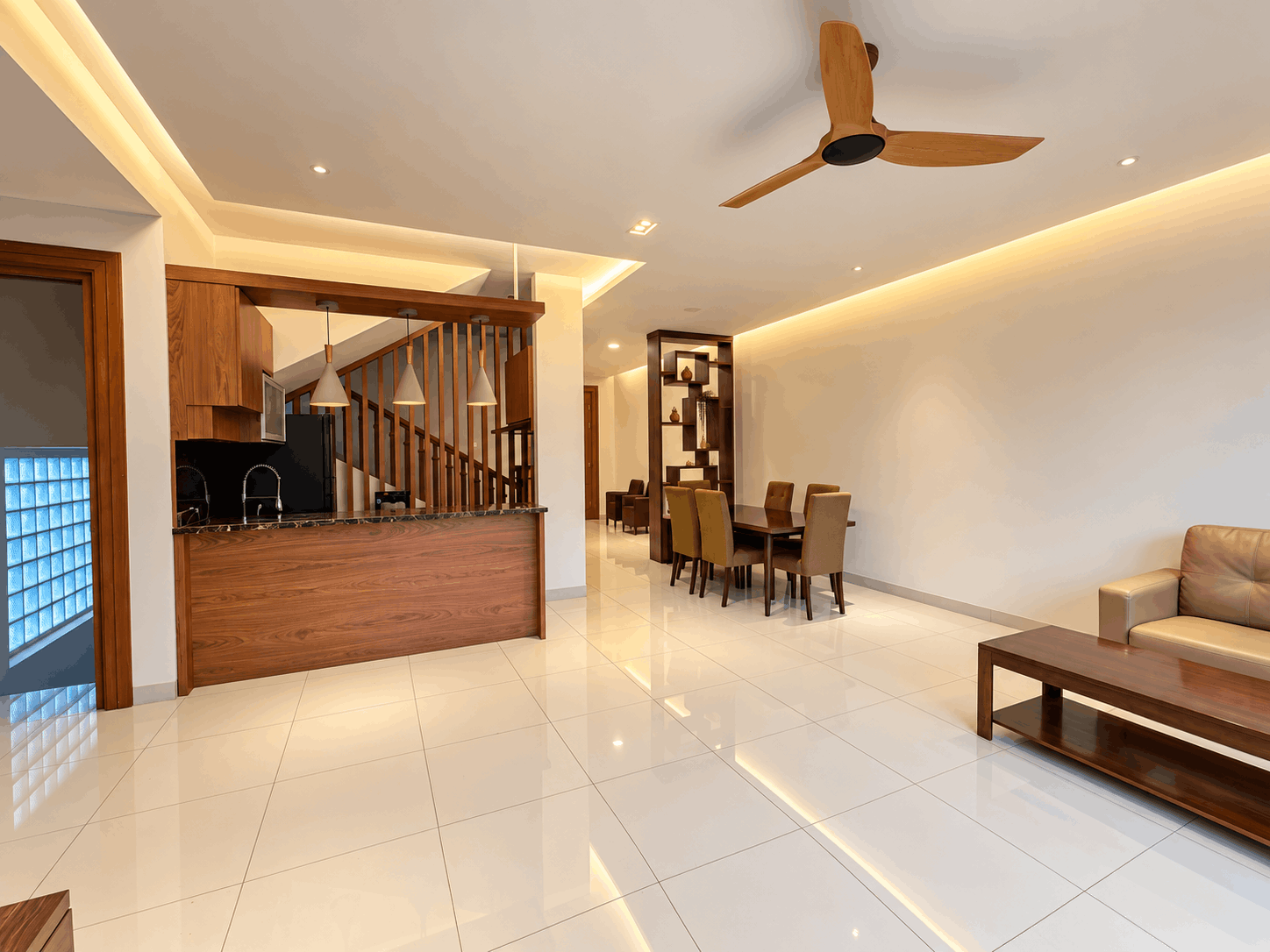 Interior open plan dengan kitchen set, meja makan, ruang duduk, dan pencahayaan indirek bernuansa hangat.